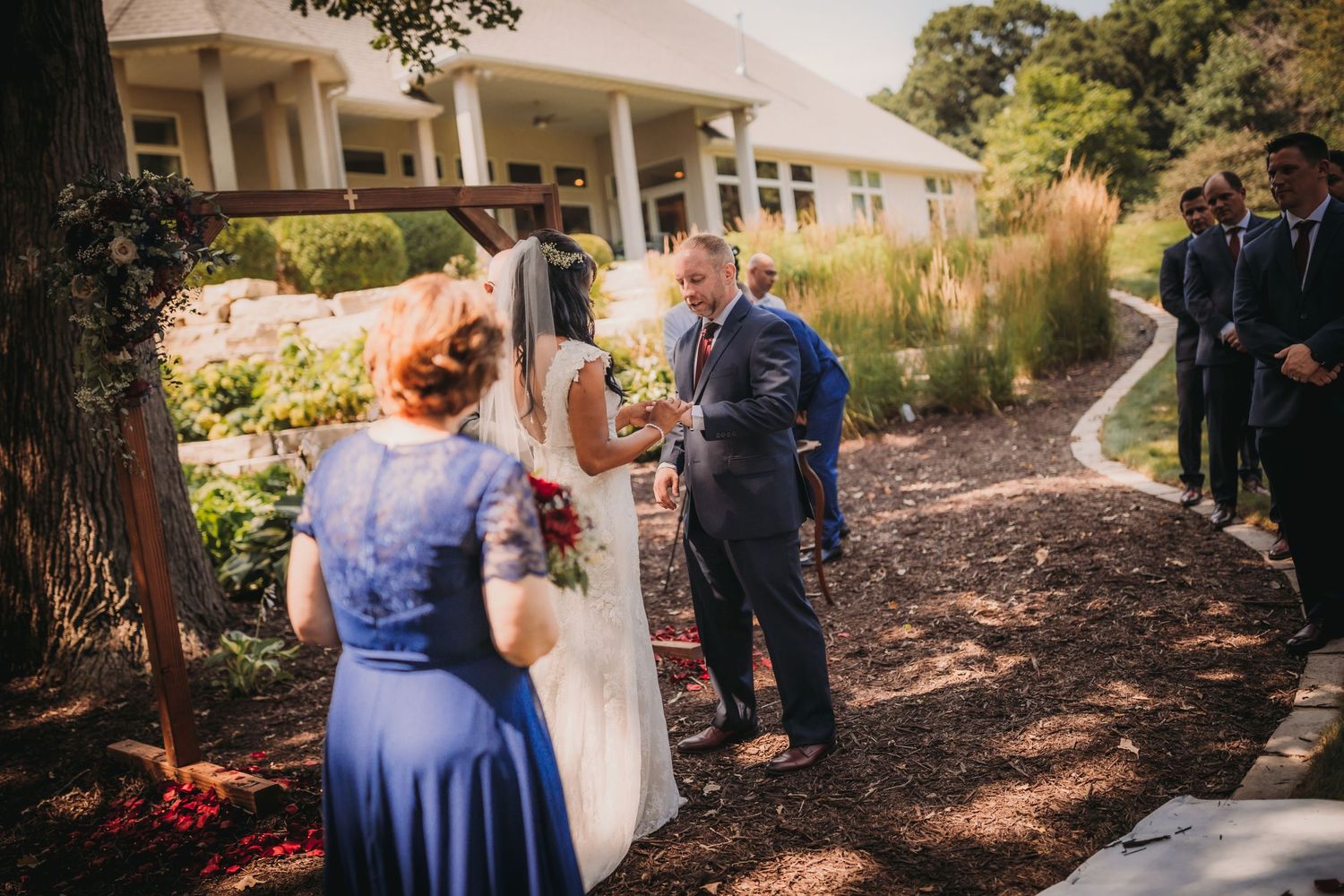 Rustic outdoor wedding venue with natural woodland backdrop and scattered seating.