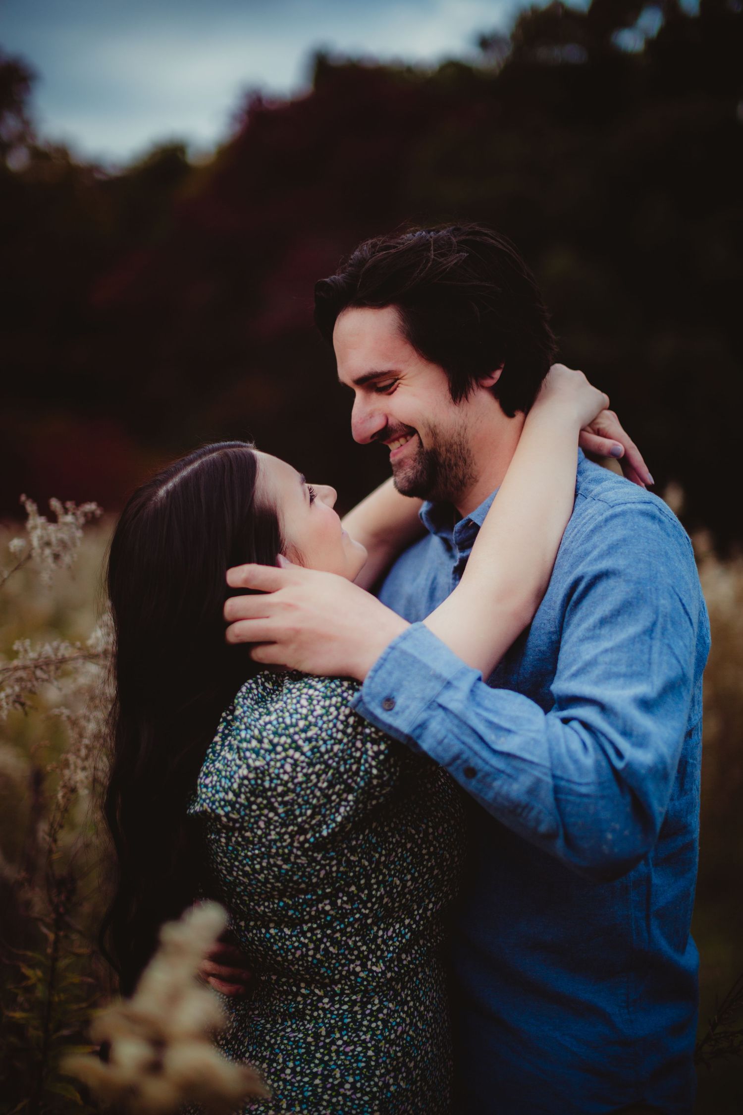 Couple in blue denim and floral dress sharing a tender moment among wildflowers.