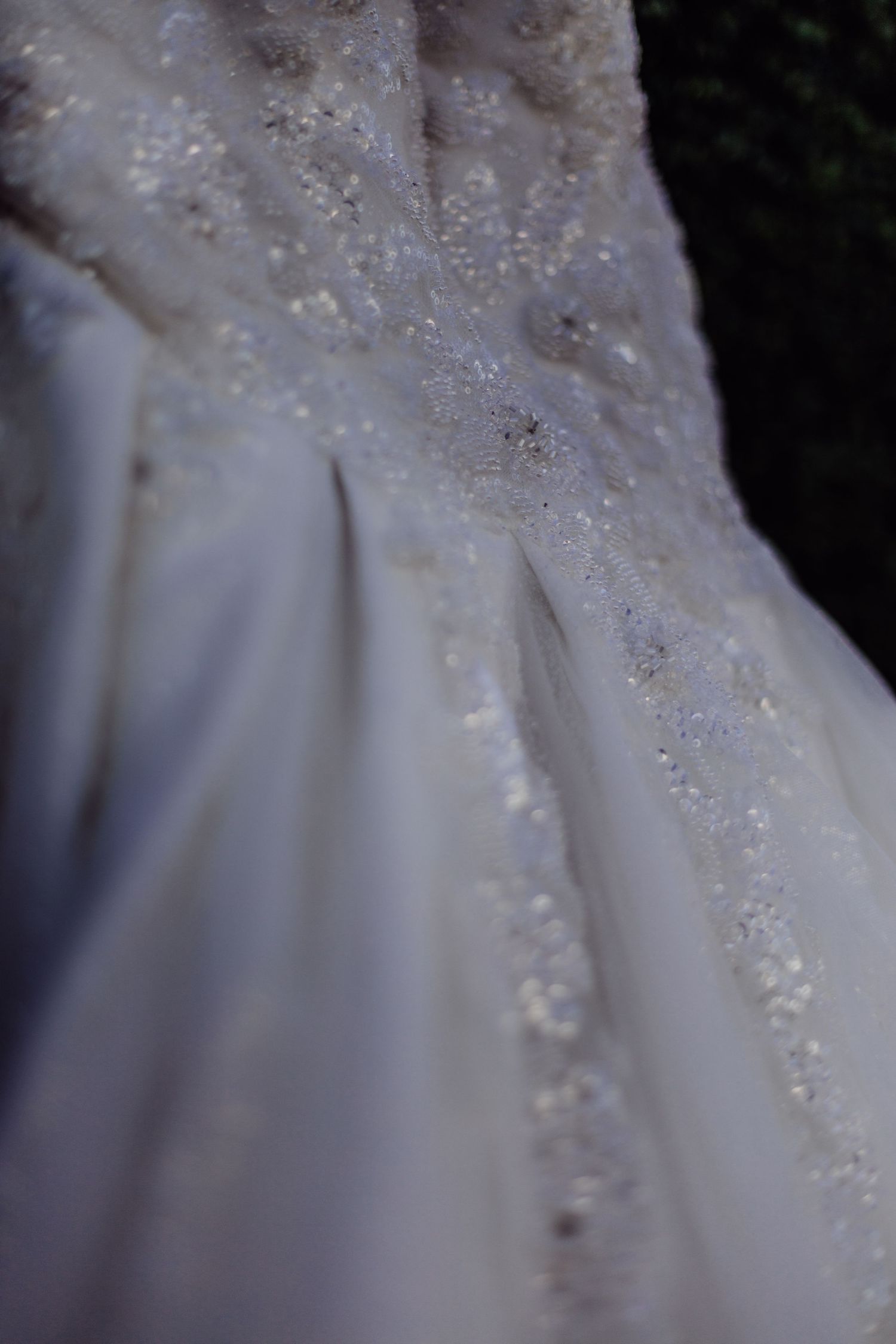 Close-up detail of delicate beadwork and lace on a white wedding dress.
