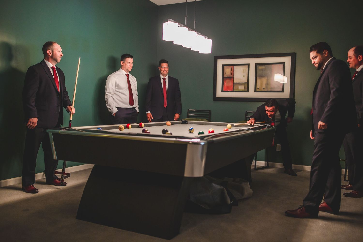 Well-dressed individuals enjoying a game of pool in a modern room with green walls.