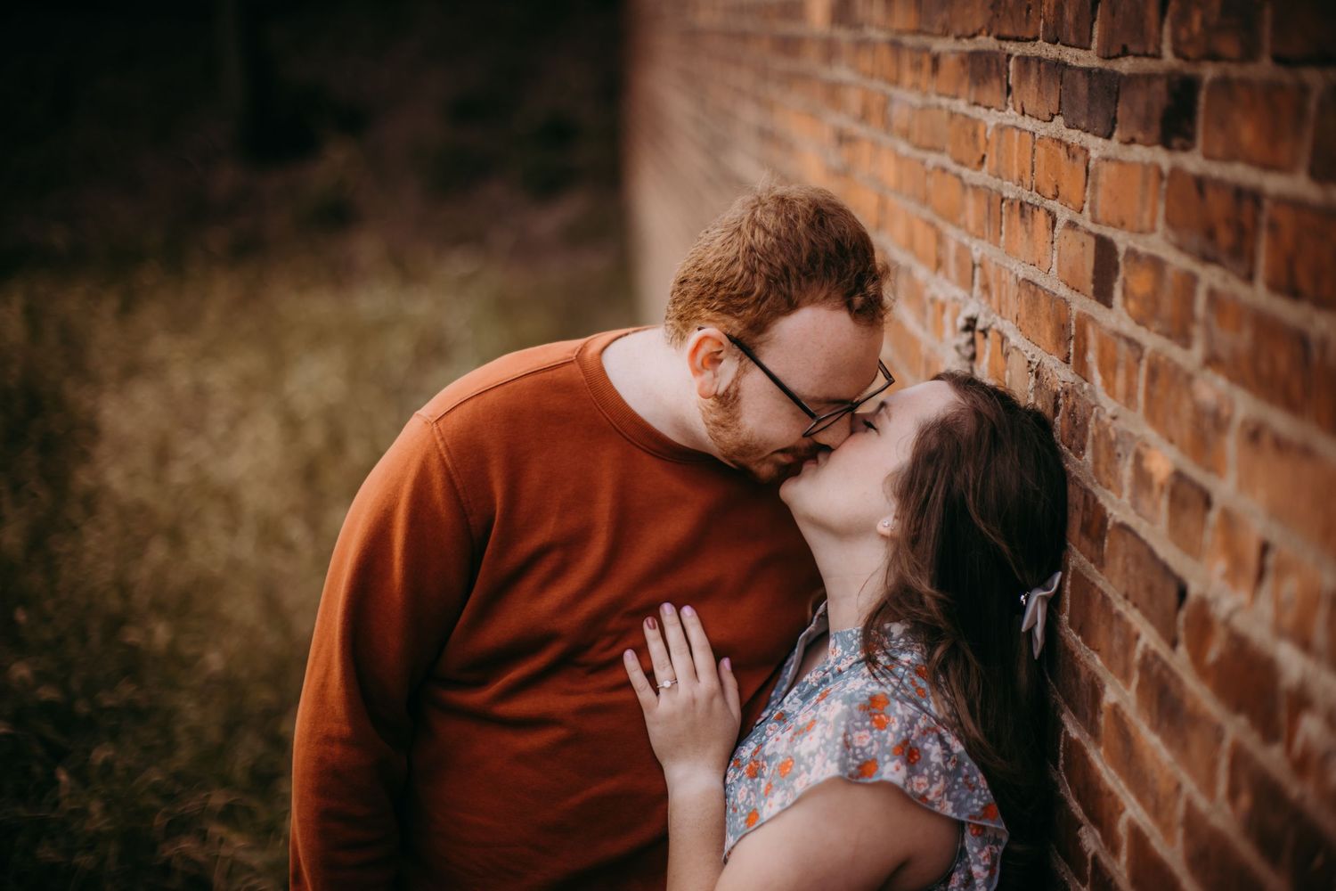 Warm-toned engagement photos capture loving moments against rustic brick textures.