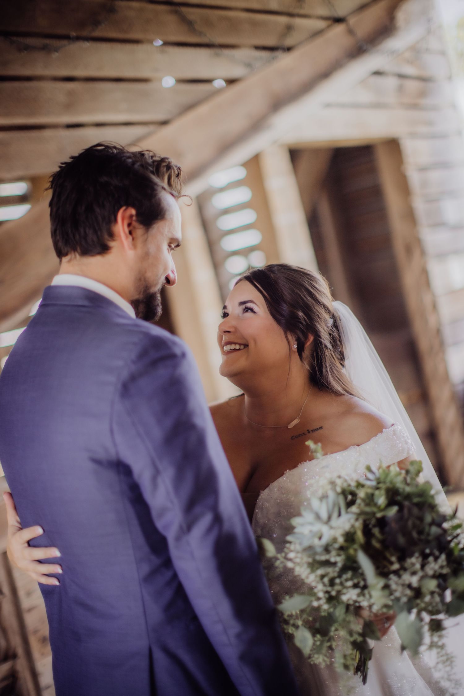Joyful wedding moment shared between couple in rustic venue with natural lighting.