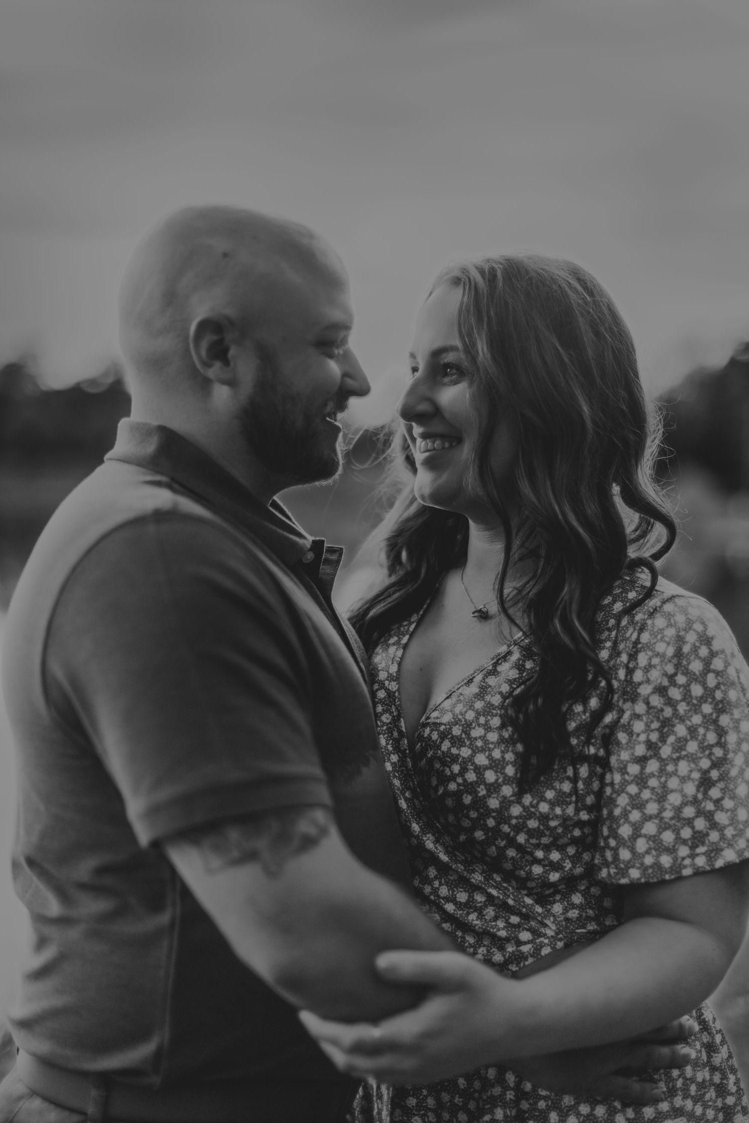 Black and white portrait of a couple sharing an intimate moment outdoors.