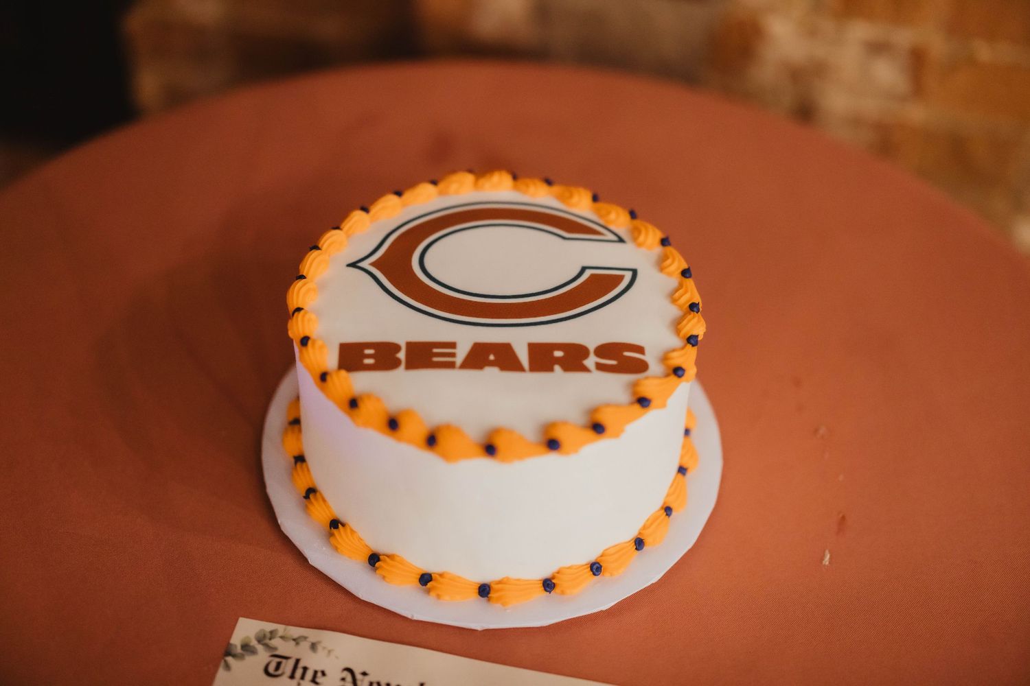 Chicago Bears themed white round cake with orange trim and team logo.