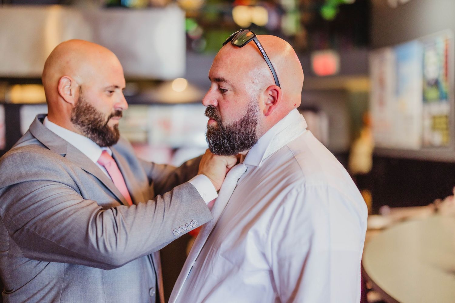 Two people helping each other adjust formal attire before event.