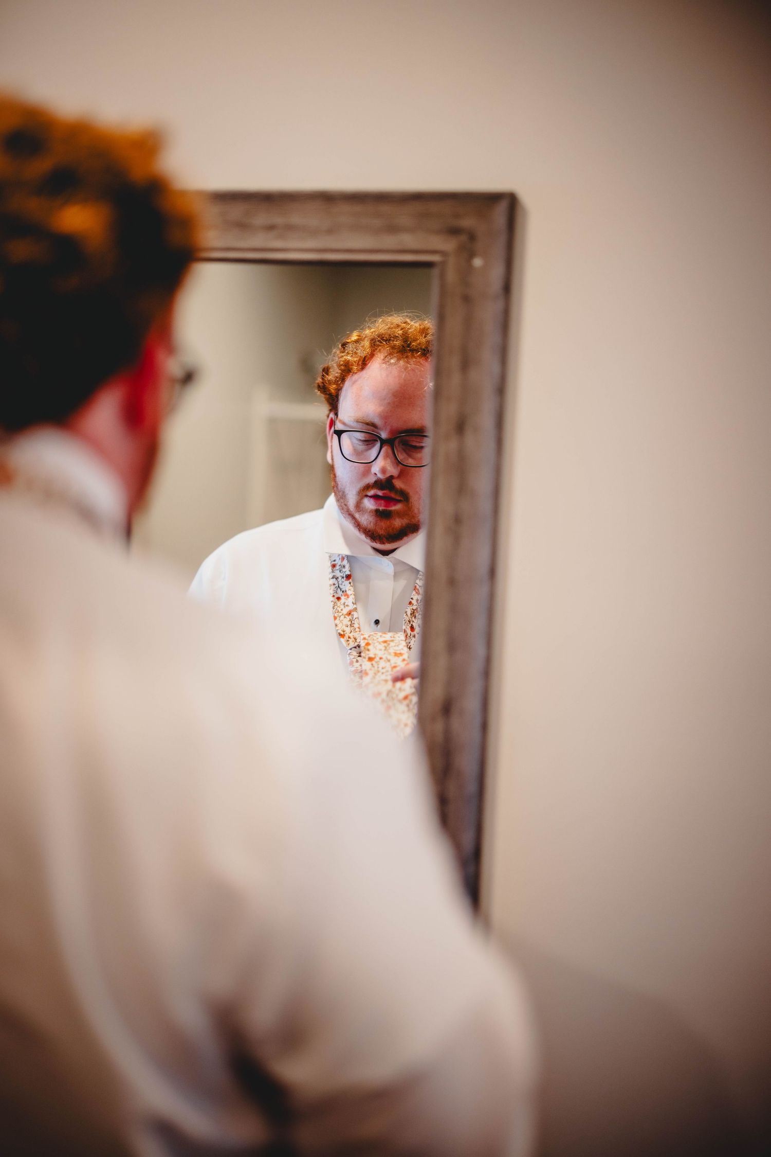 A reflection of someone adjusting their outfit in a wooden framed mirror.