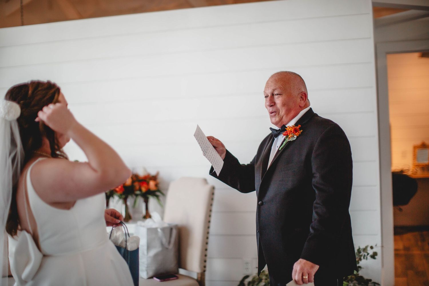 Person in formal attire reads from papers during an emotional wedding moment.