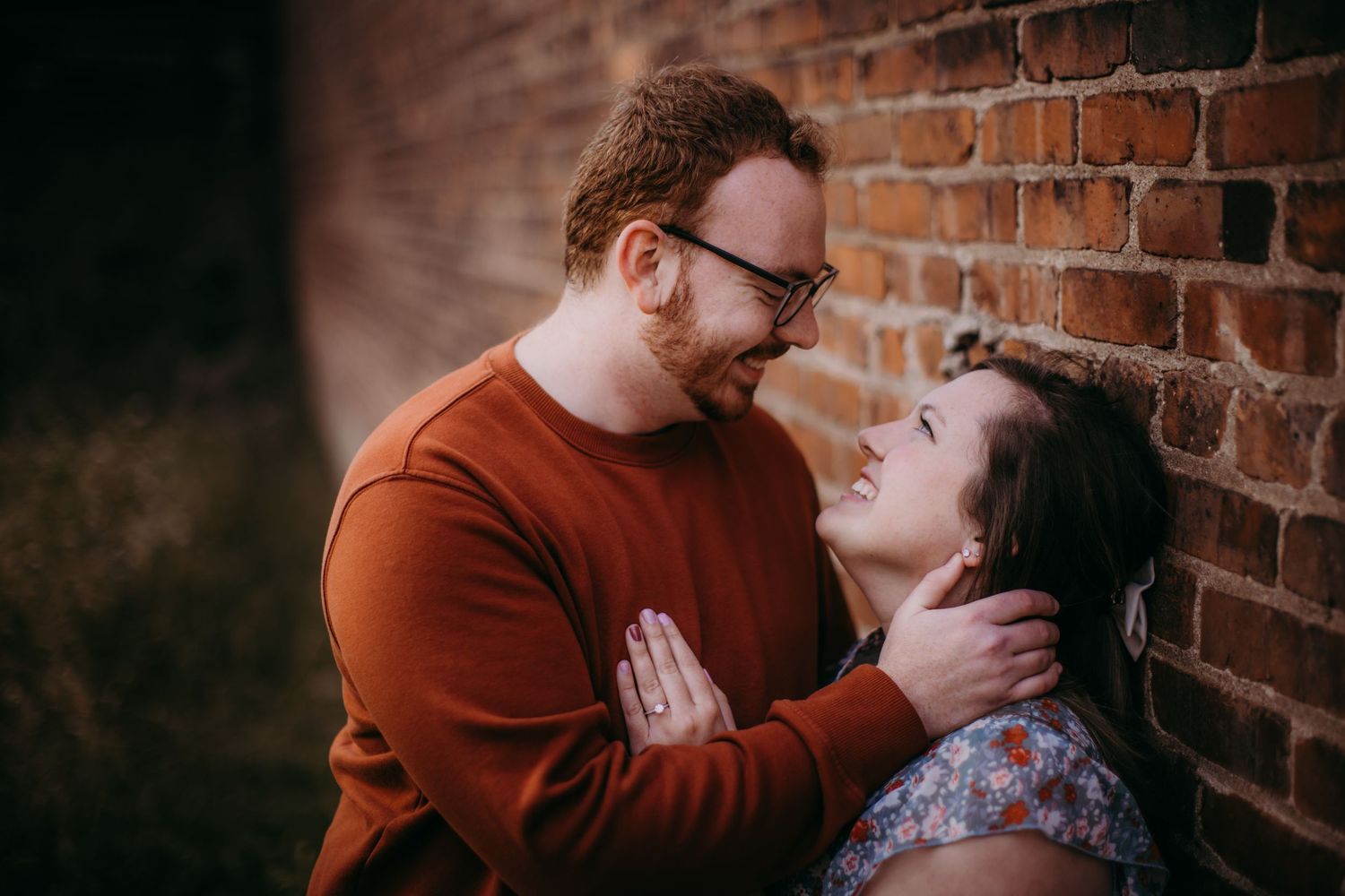 A romantic outdoor couples photoshoot against a rustic brick wall background.