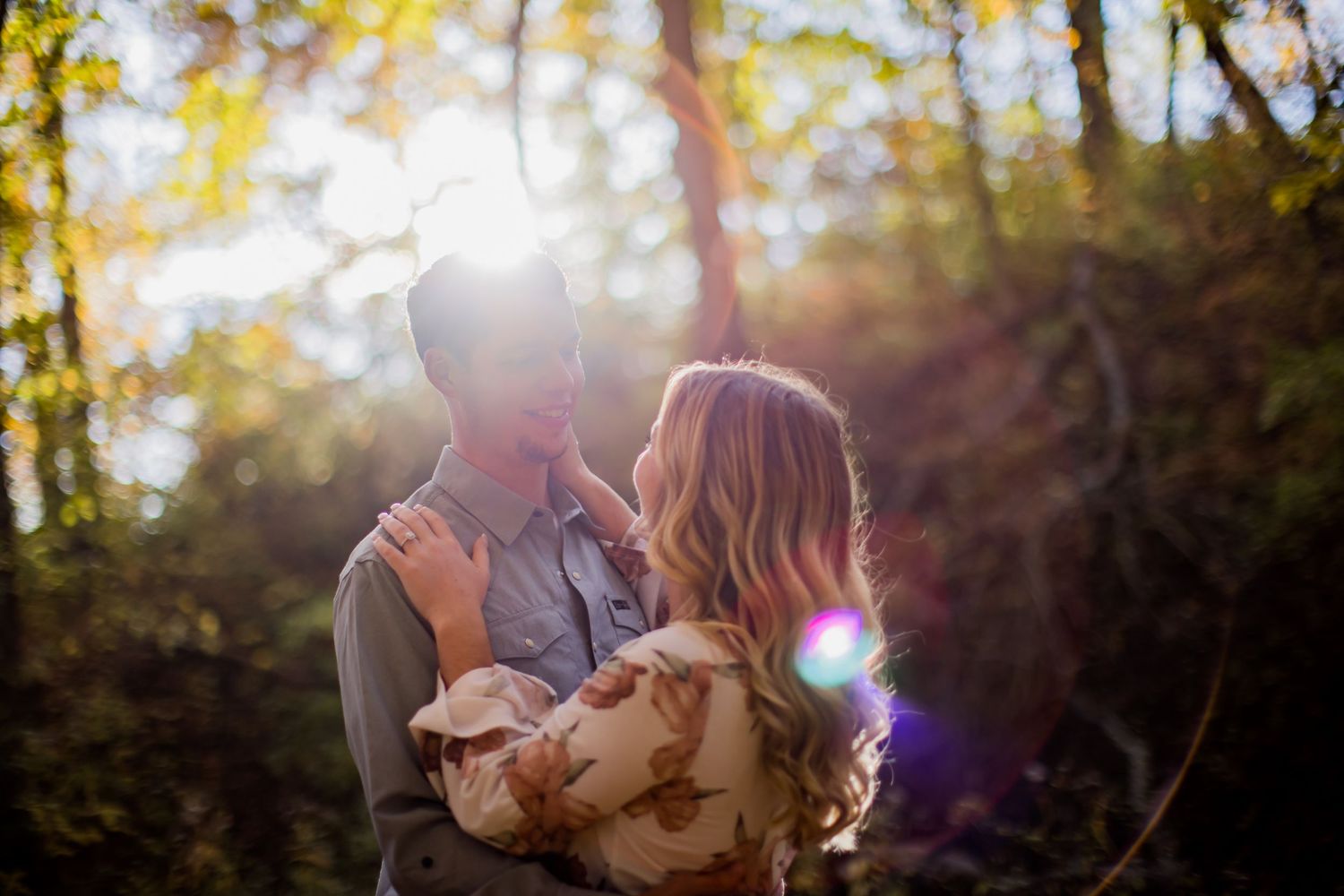 Romantic couple sharing an intimate moment in golden sunlight filtering through autumn trees.