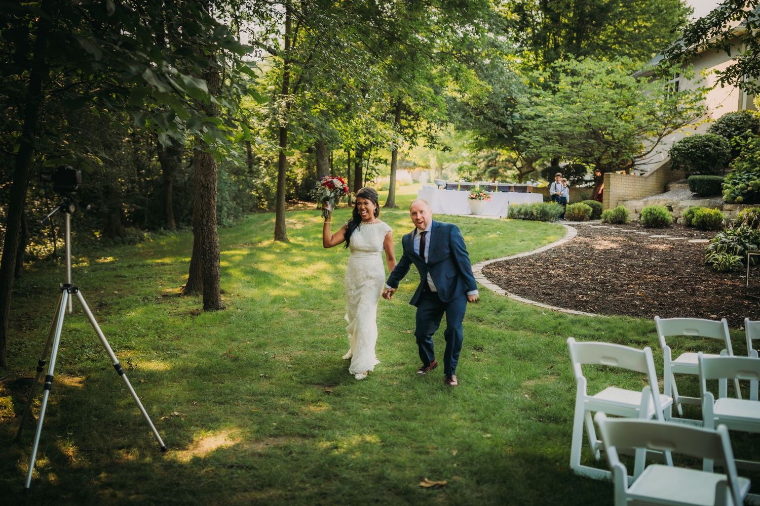 Wedding ceremony setup with white chairs in a tranquil wooded outdoor setting.
