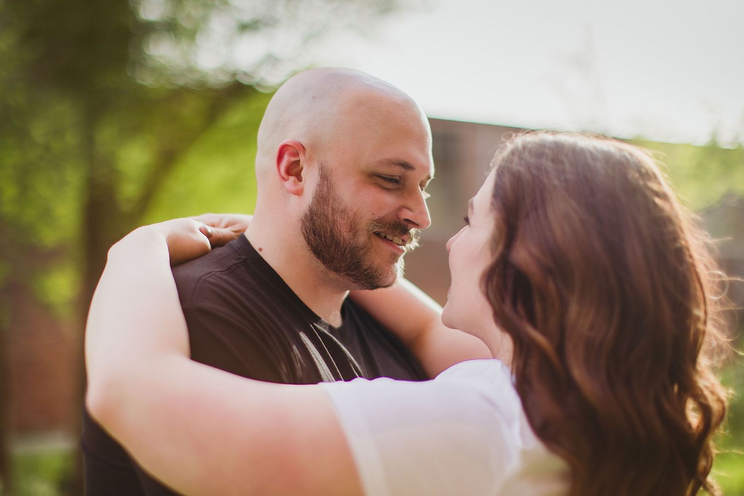 A tender moment between a couple sharing laughter while embracing outdoors.