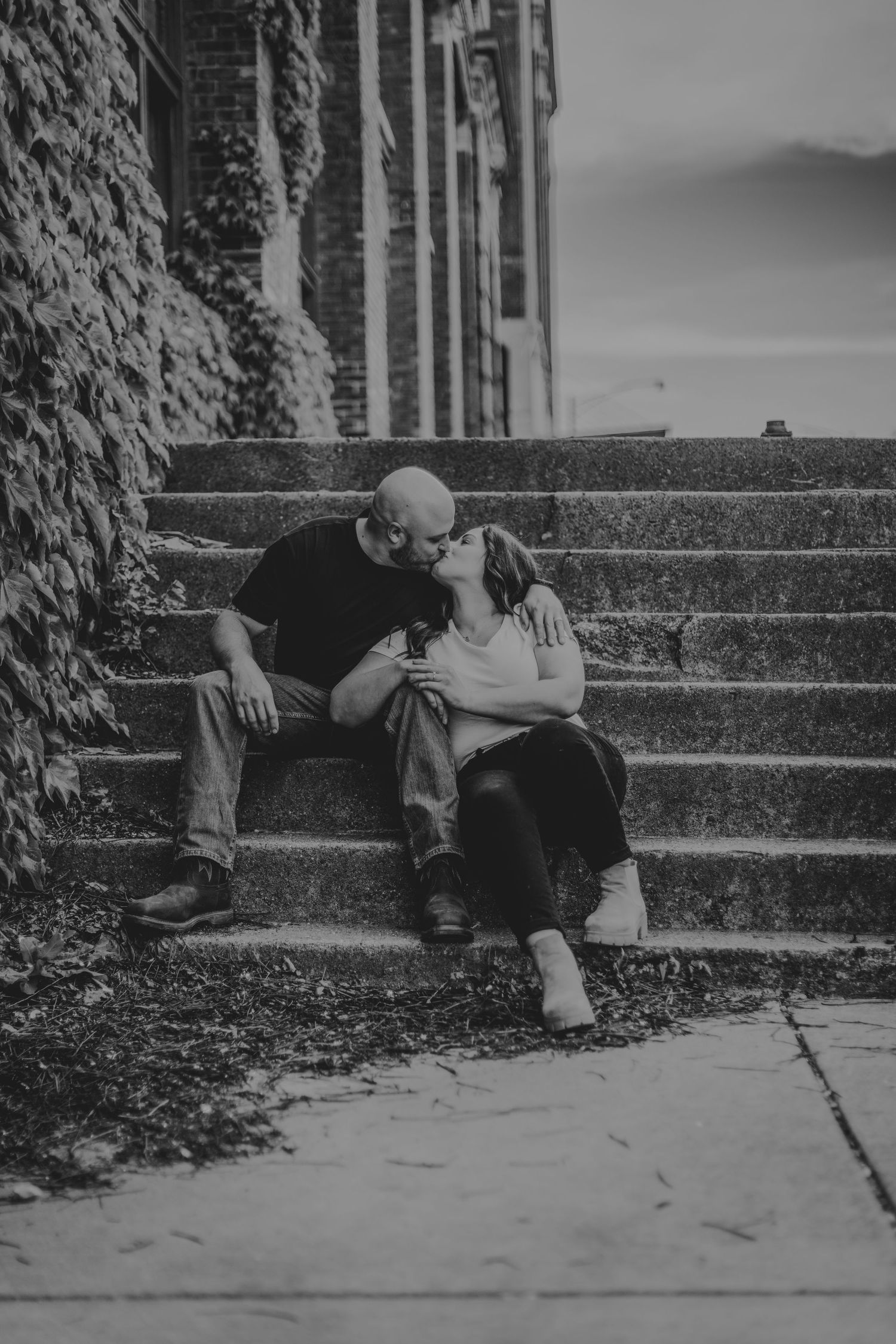 Black and white portrait of a couple lounging intimately on outdoor stone steps.