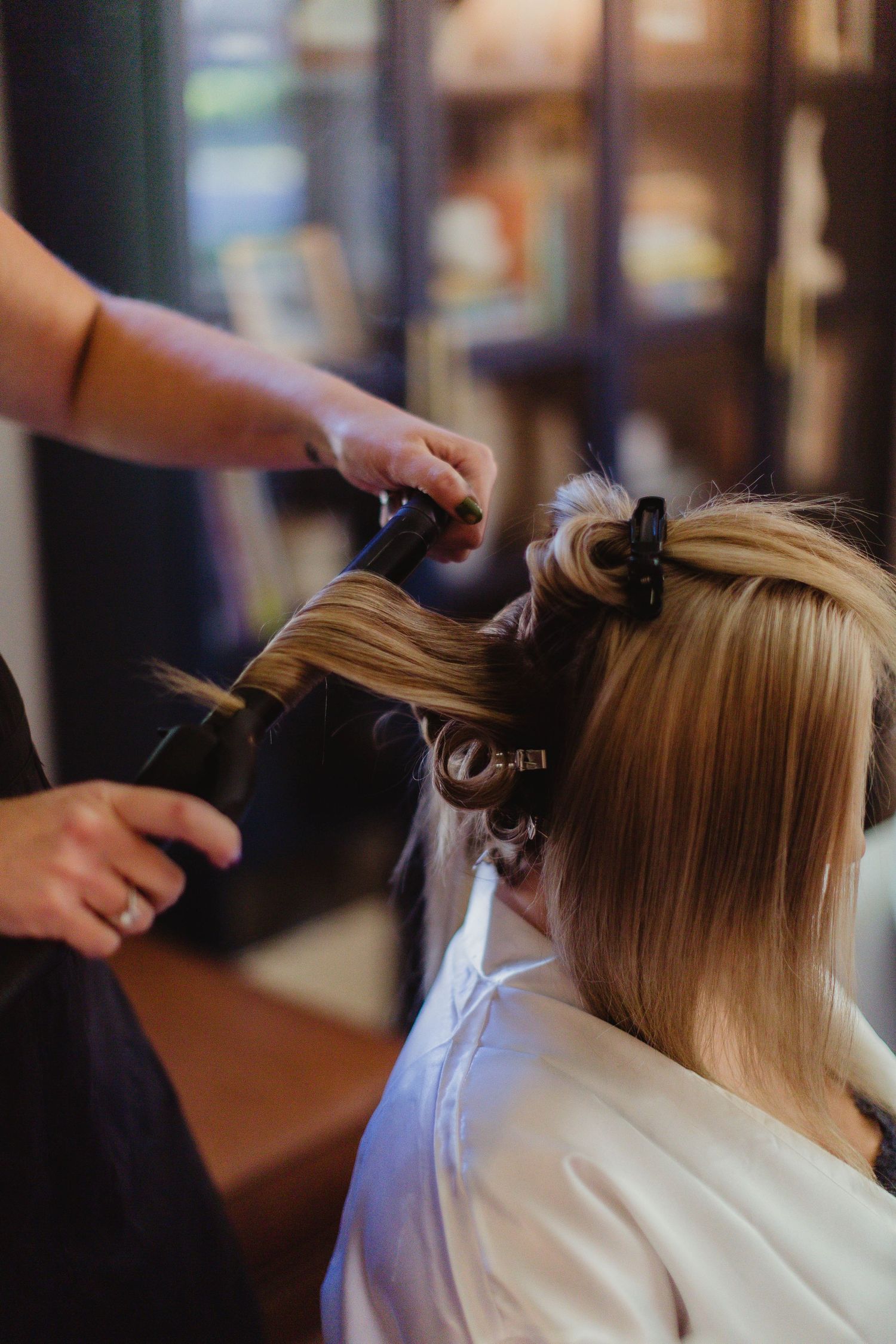 Hair styling session in progress with professional tools and white robe.