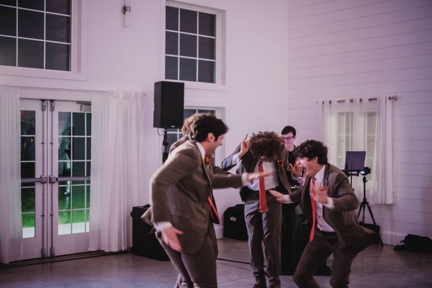 People enjoying themselves on the dance floor at an indoor celebration with white decor.