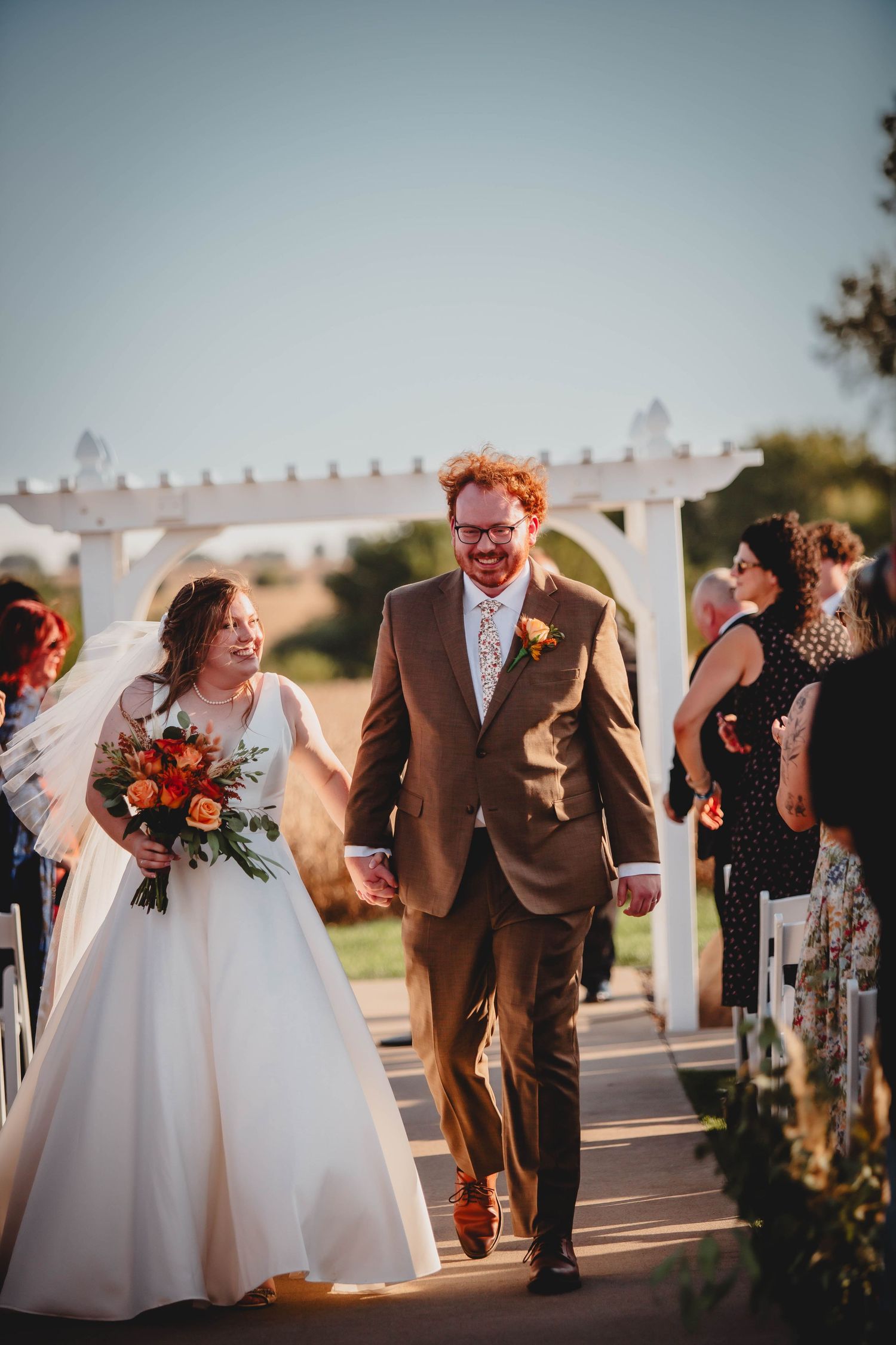 Couple walking down aisle after outdoor wedding ceremony.