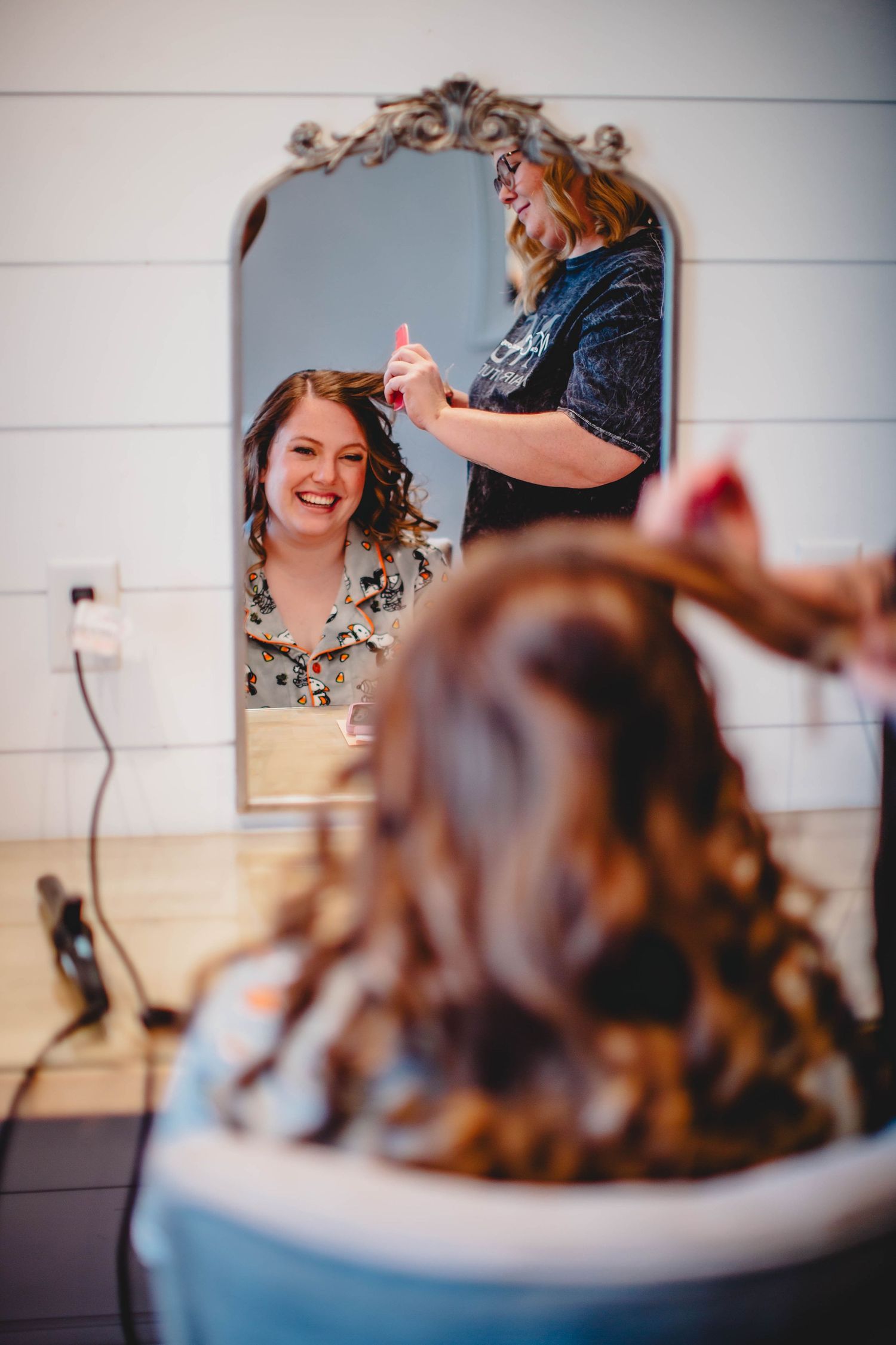 A hair styling session captured in an ornate mirror reflection.
