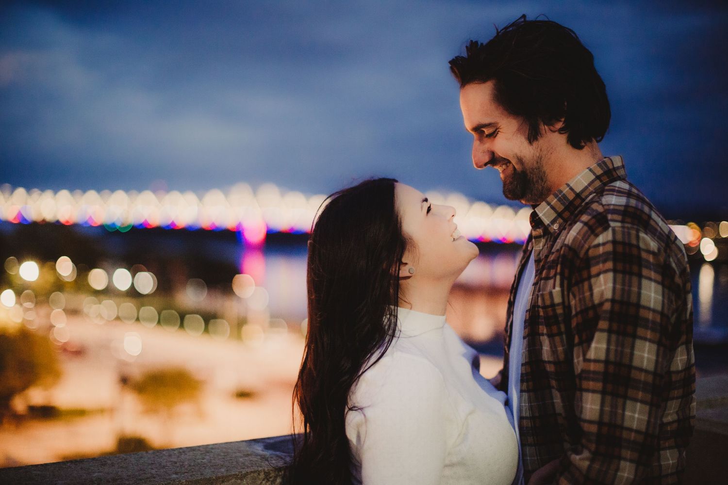 Silhouettes of a couple against an evening cityscape with bokeh lights.