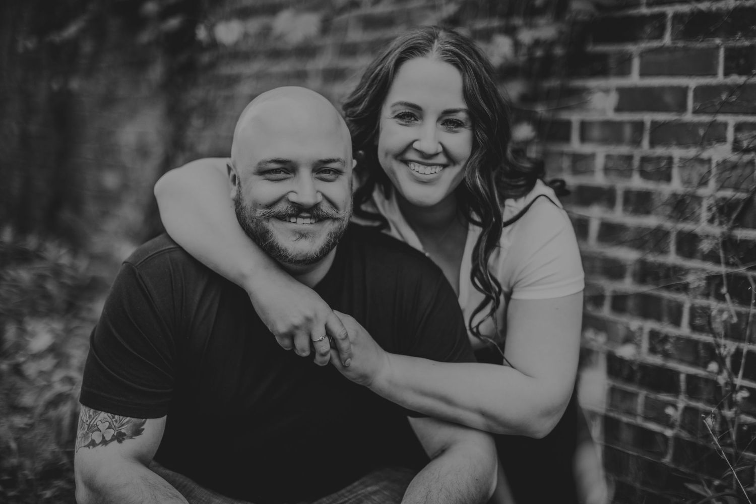 Close-up black and white sequence of couple sharing loving embraces against brick wall background.