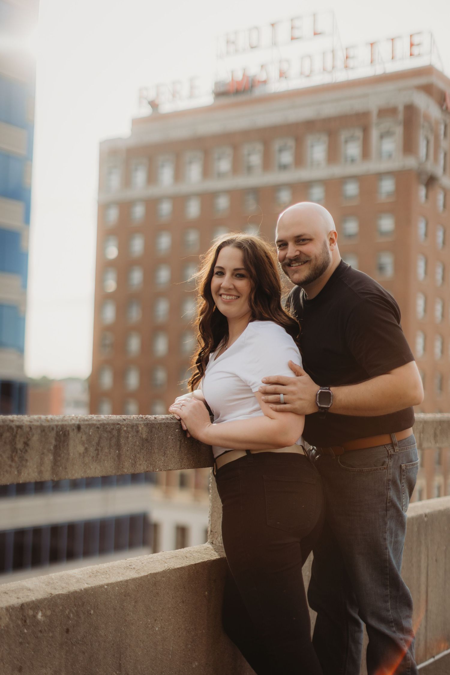 A romantic couple's portrait taken at sunset with downtown architecture in the background.