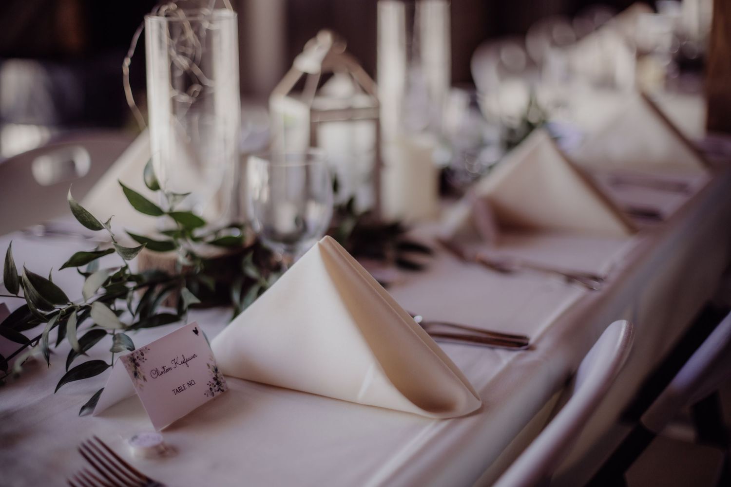 Formal place settings with white napkins and silverware at round tables.