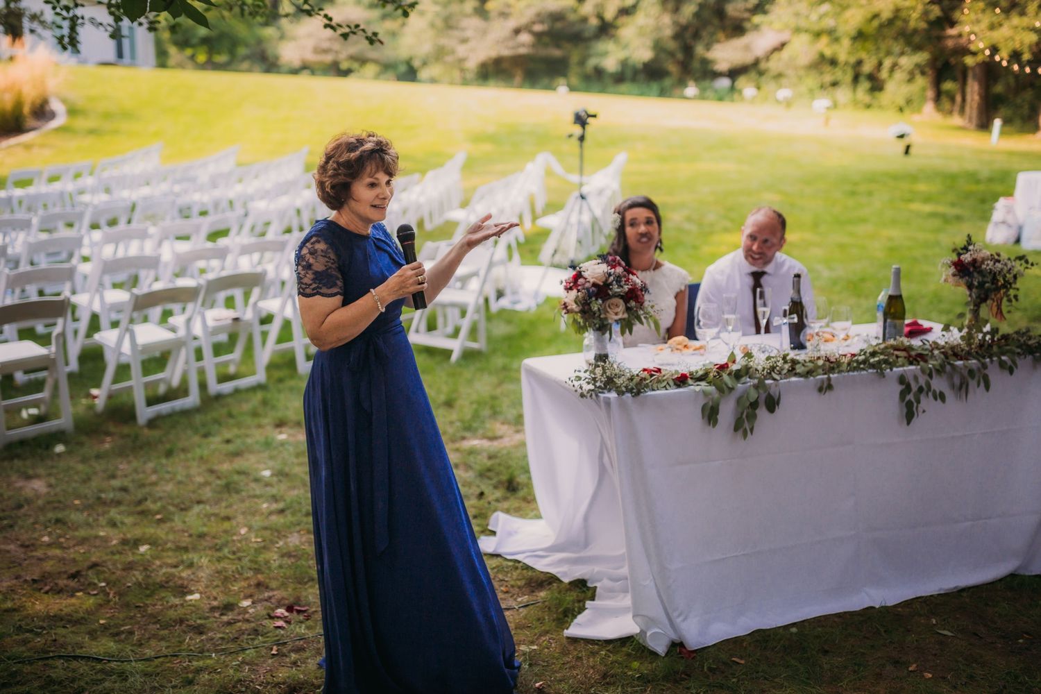Wedding reception setup featuring navy blue accents and white tables in a garden setting.