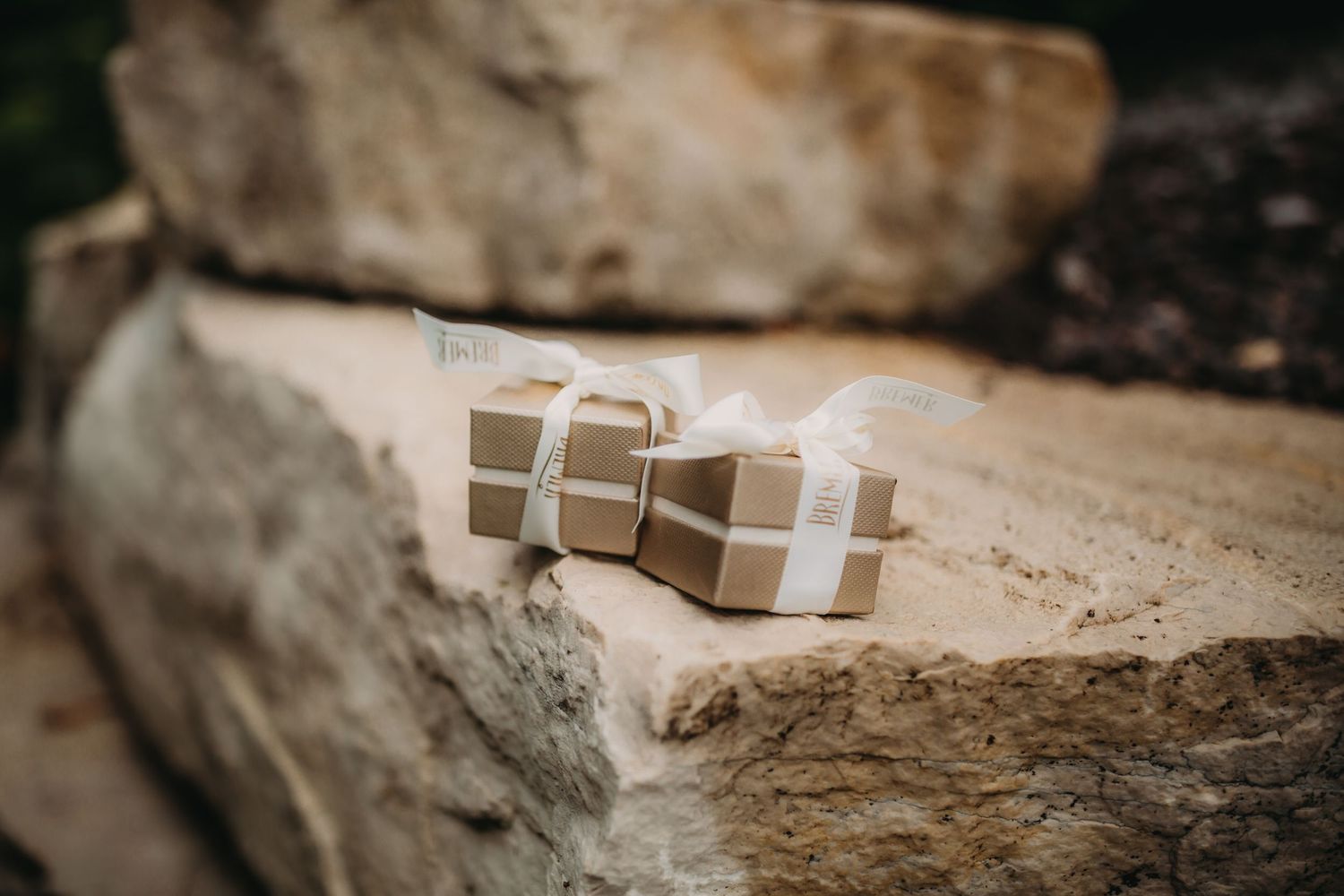 Elegant beige wedding ring box placed on textured stone surface.