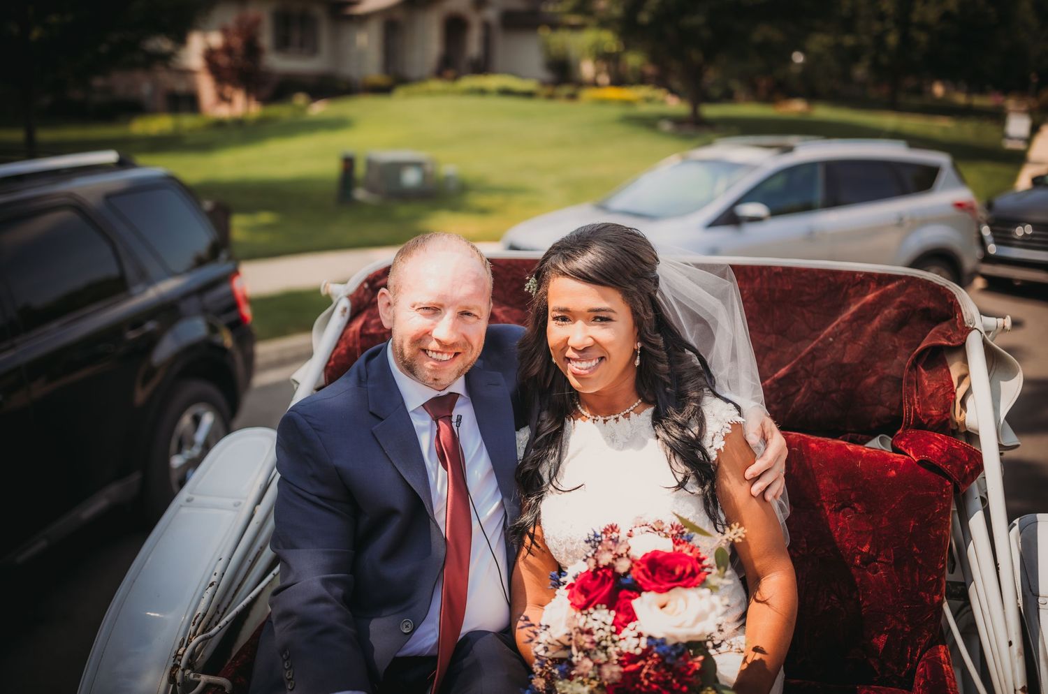A happy couple seated in a white vintage-style carriage on their wedding day.