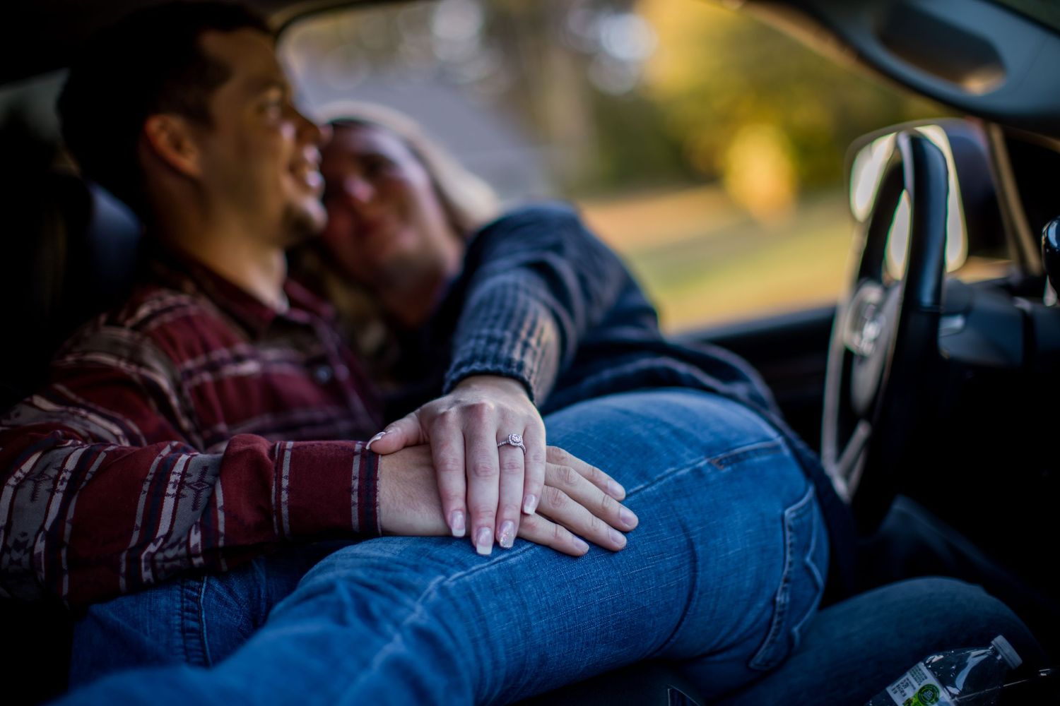 Close-up view of denim and plaid clothing in car interior.
