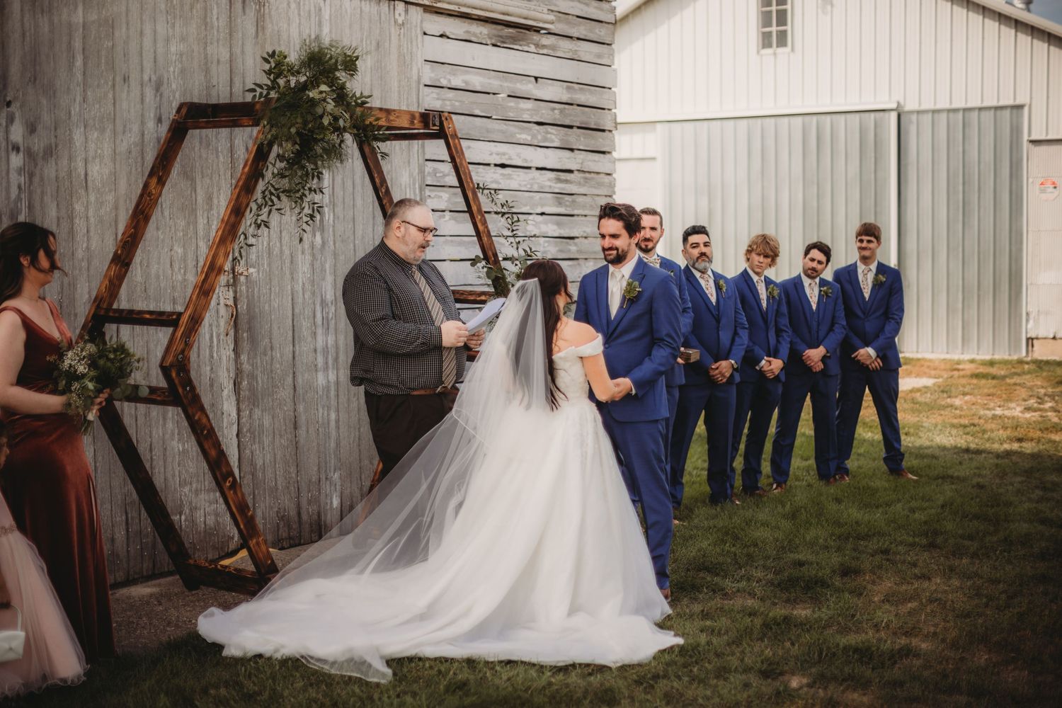 Rustic barn wedding venue decorated with wooden arch and floral arrangements.