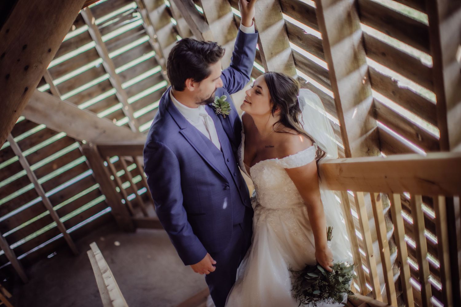 Newlywed couple sharing a romantic moment in a wooden architectural structure.
