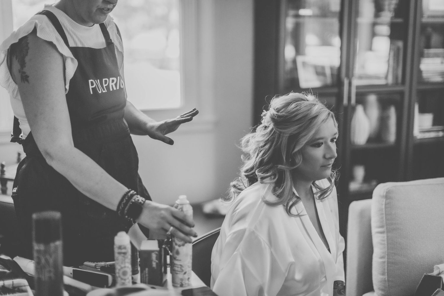 Wedding preparation scene with stylist and client in black and white.