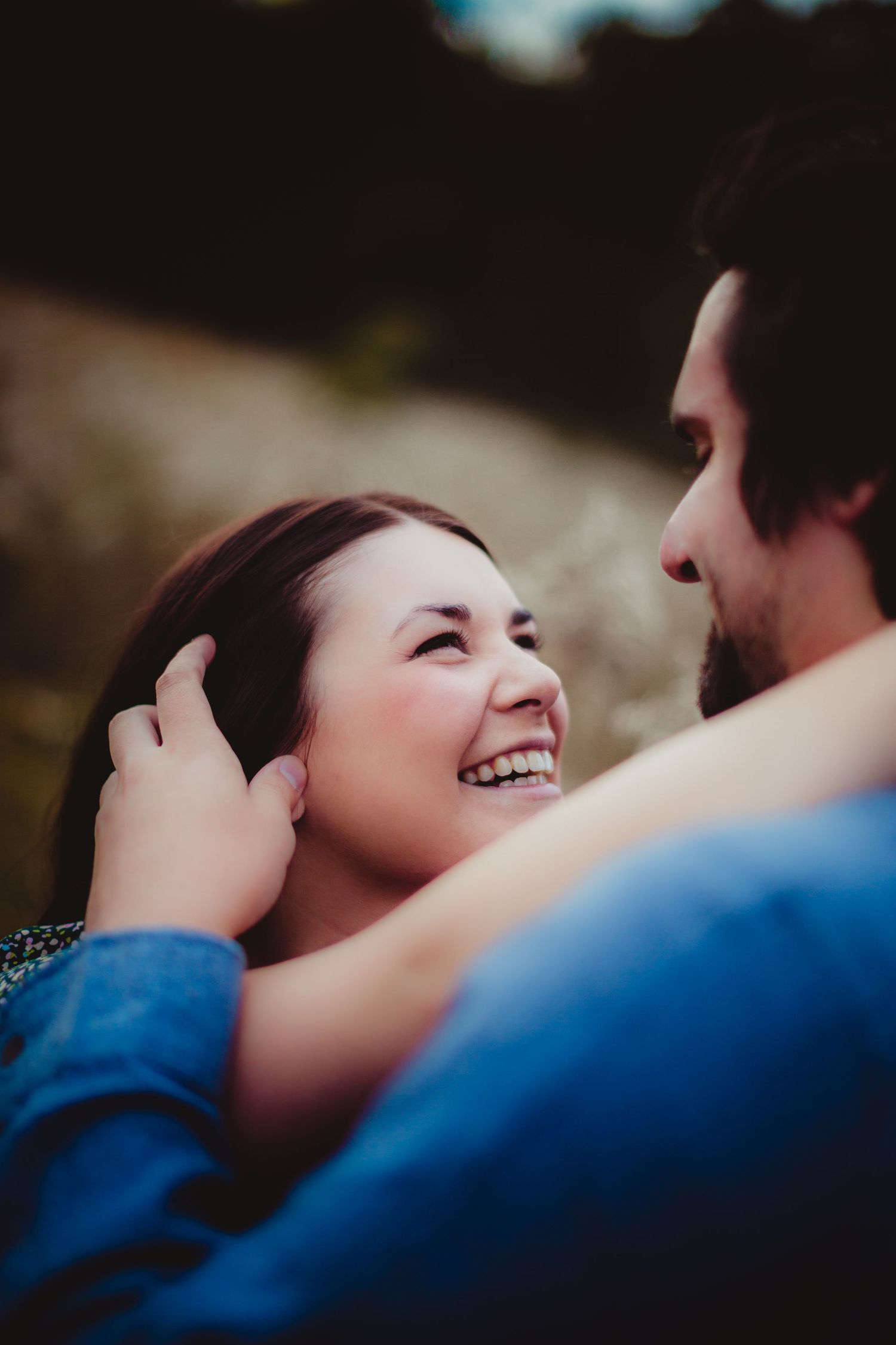 Close-up side profile of a couple sharing a joyful moment outdoors.