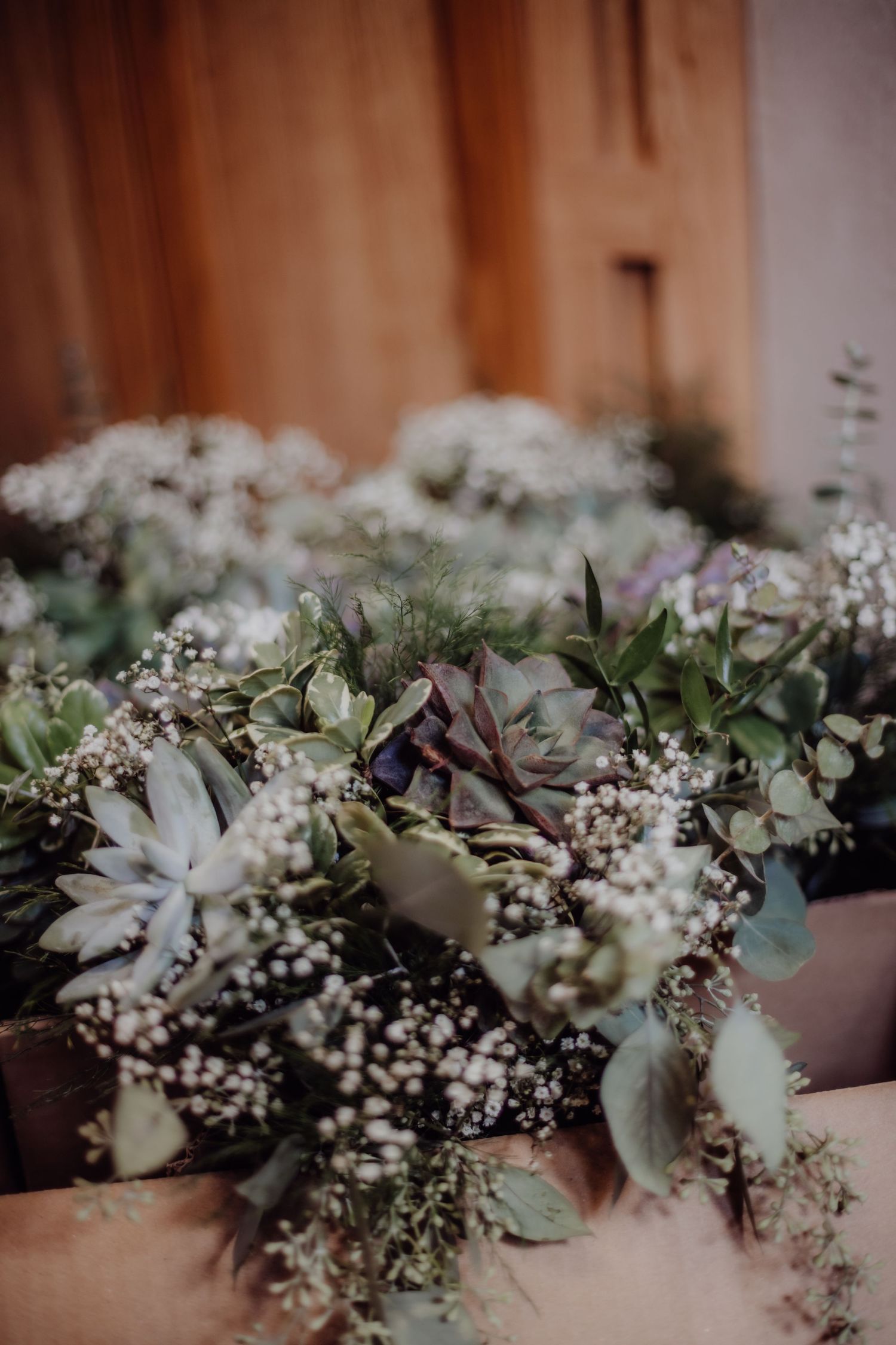 Elegant floral table runner with white flowers, greenery and eucalyptus leaves.