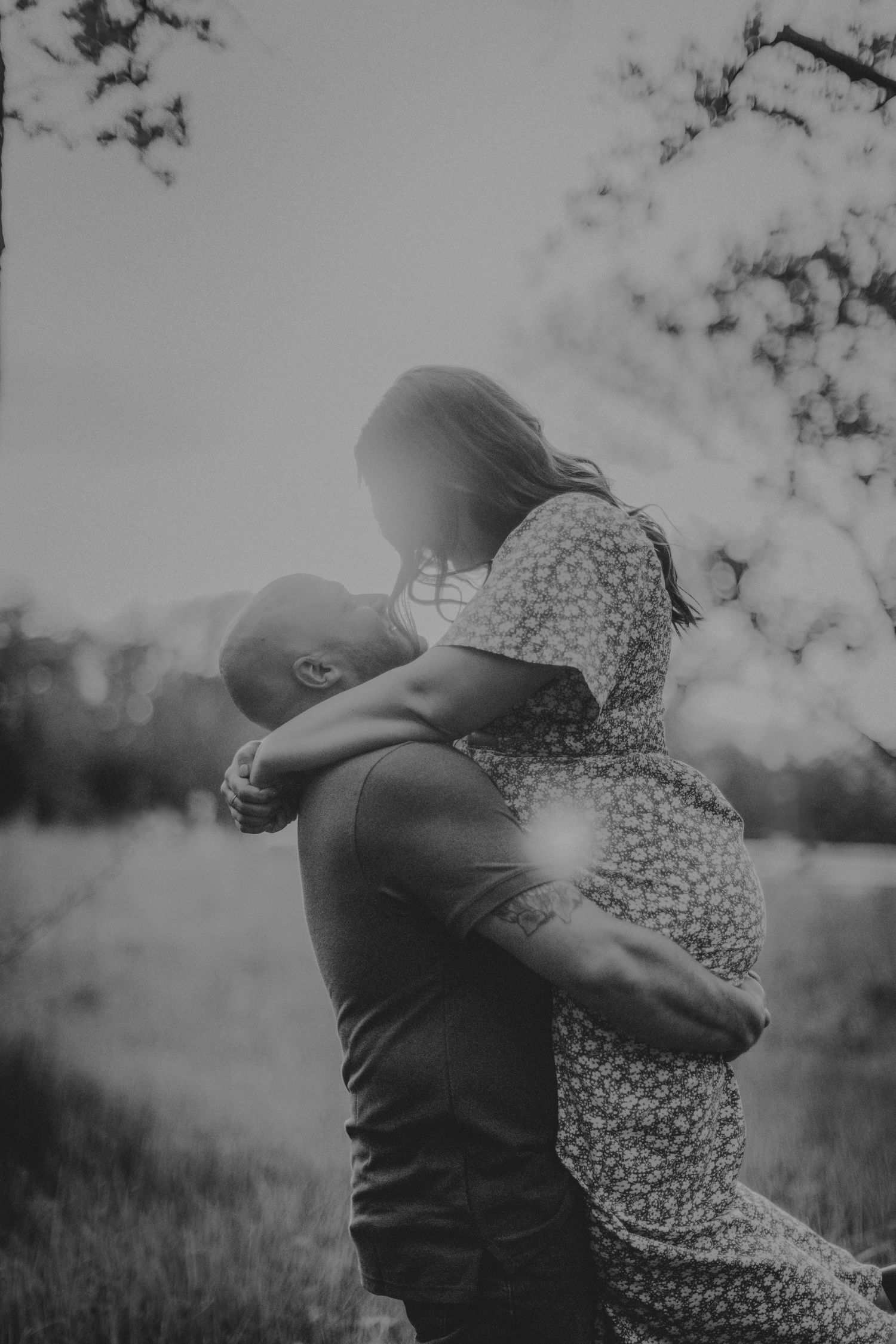 Artistic black and white photo of a couple sharing a romantic embrace in nature.
