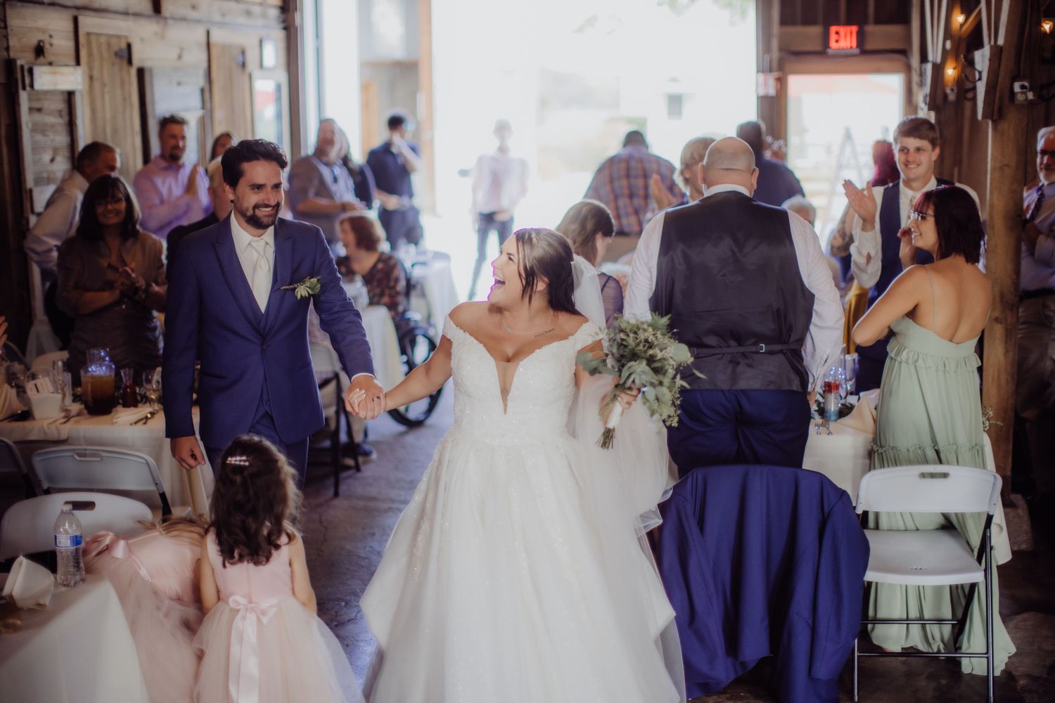 Wedding celebration in progress inside a rustic barn venue with dancing guests.