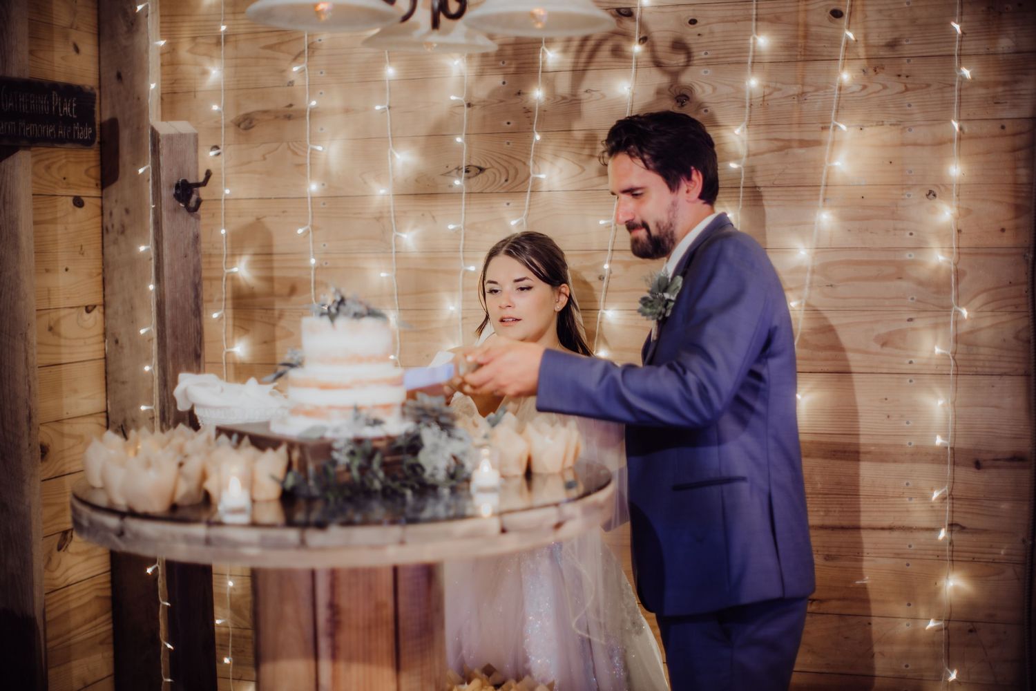 Couple enjoying their first bite of wedding cake together at their rustic reception.
