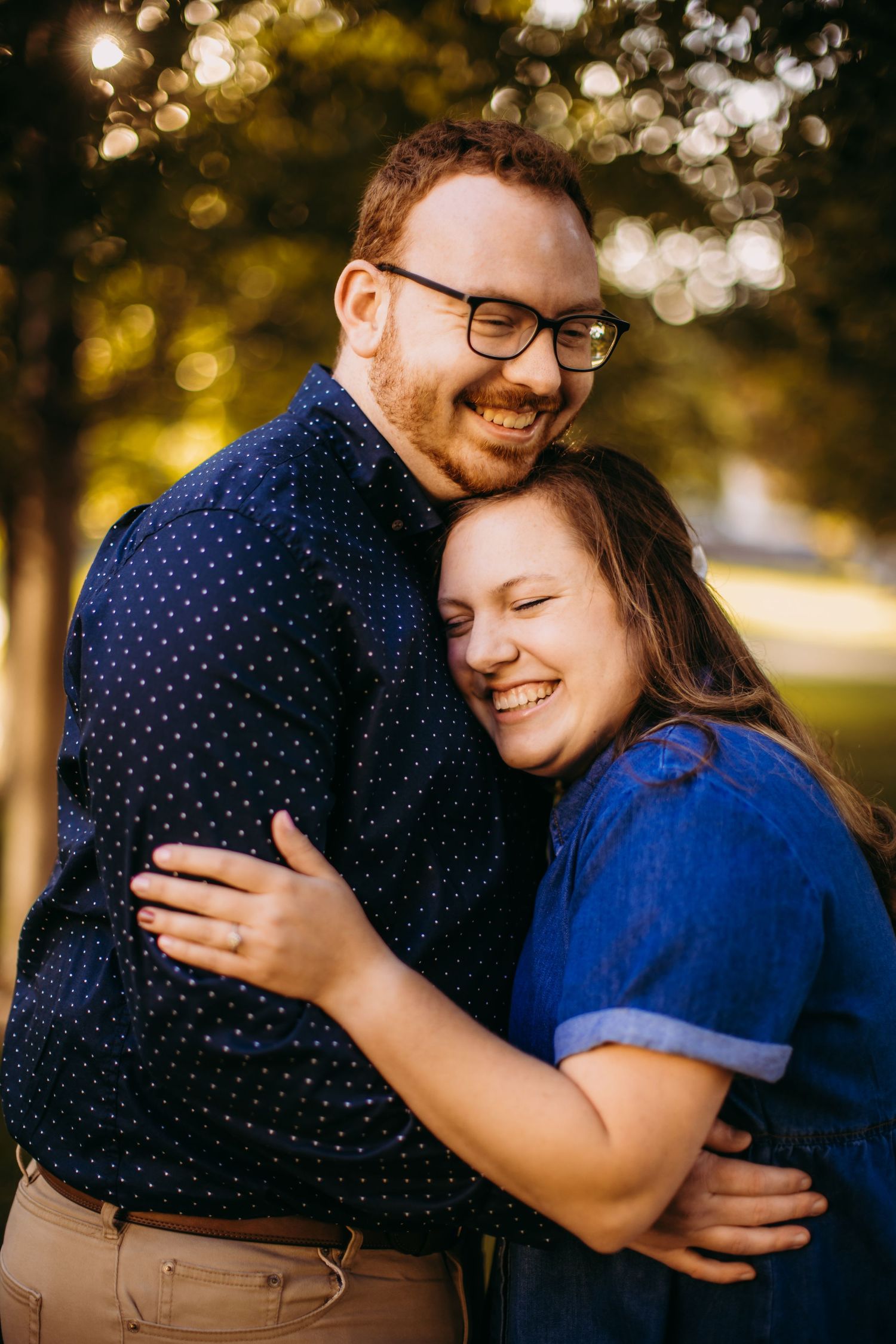 Candid portrait of a couple laughing together against golden bokeh background.