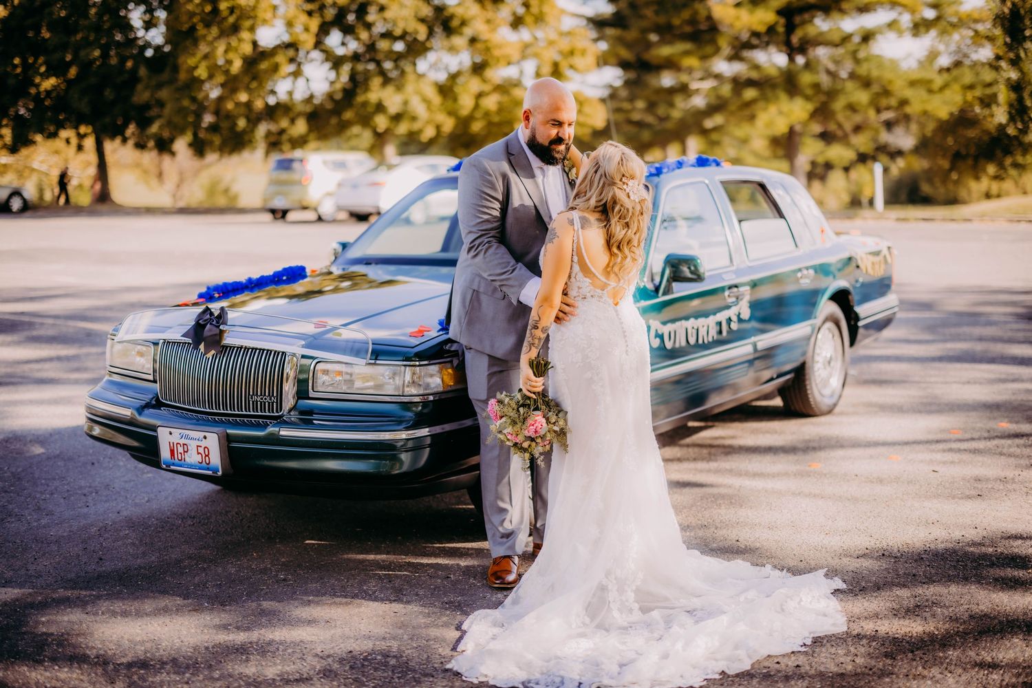 Wedding portrait with classic Lincoln car in sunlit outdoor setting with fall foliage.