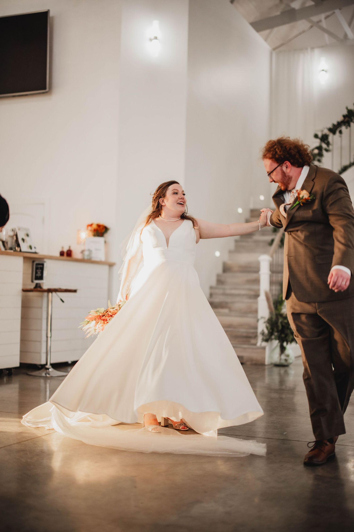 A couple dances together at their wedding, with the bride's white dress flowing gracefully around them.