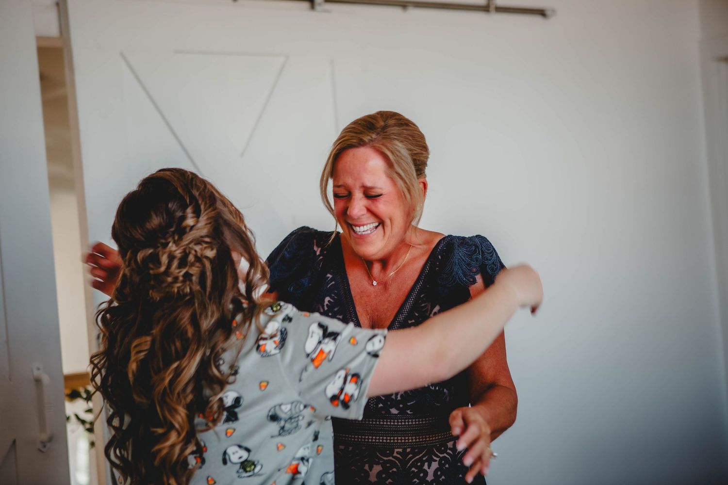 Two people sharing an emotional embrace during a wedding first look in a light-filled room.