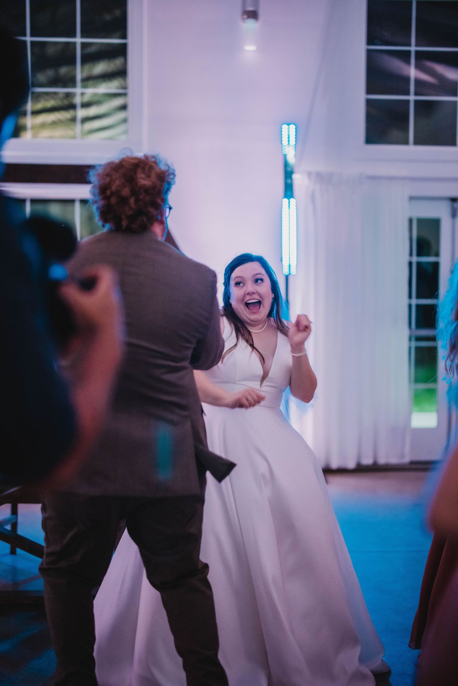 A bride in a white dress dances enthusiastically at her wedding reception.