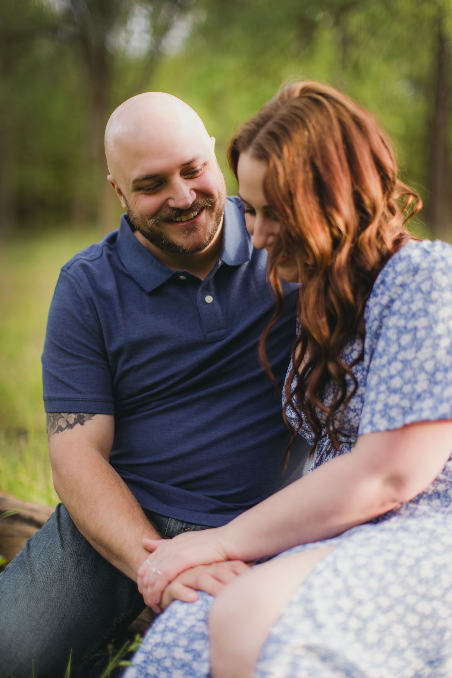 Couple in casual attire sharing a tender moment while sitting together in a natural outdoor setting.
