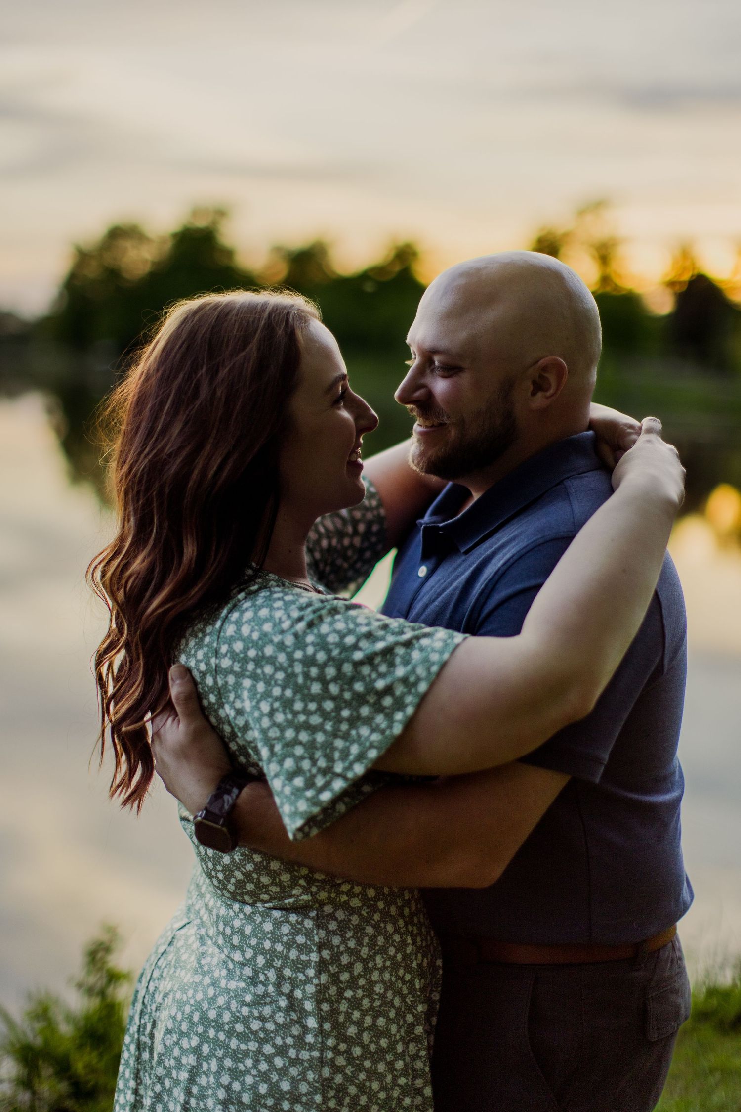 An intimate moment shared between a couple against a sunset lakeside backdrop.