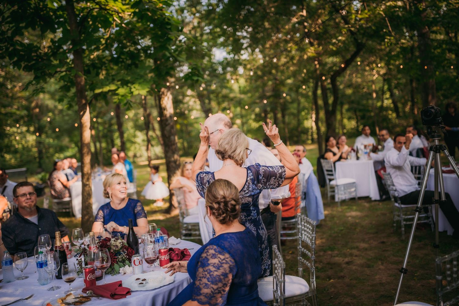 Outdoor wedding reception with guests mingling among decorated tables.