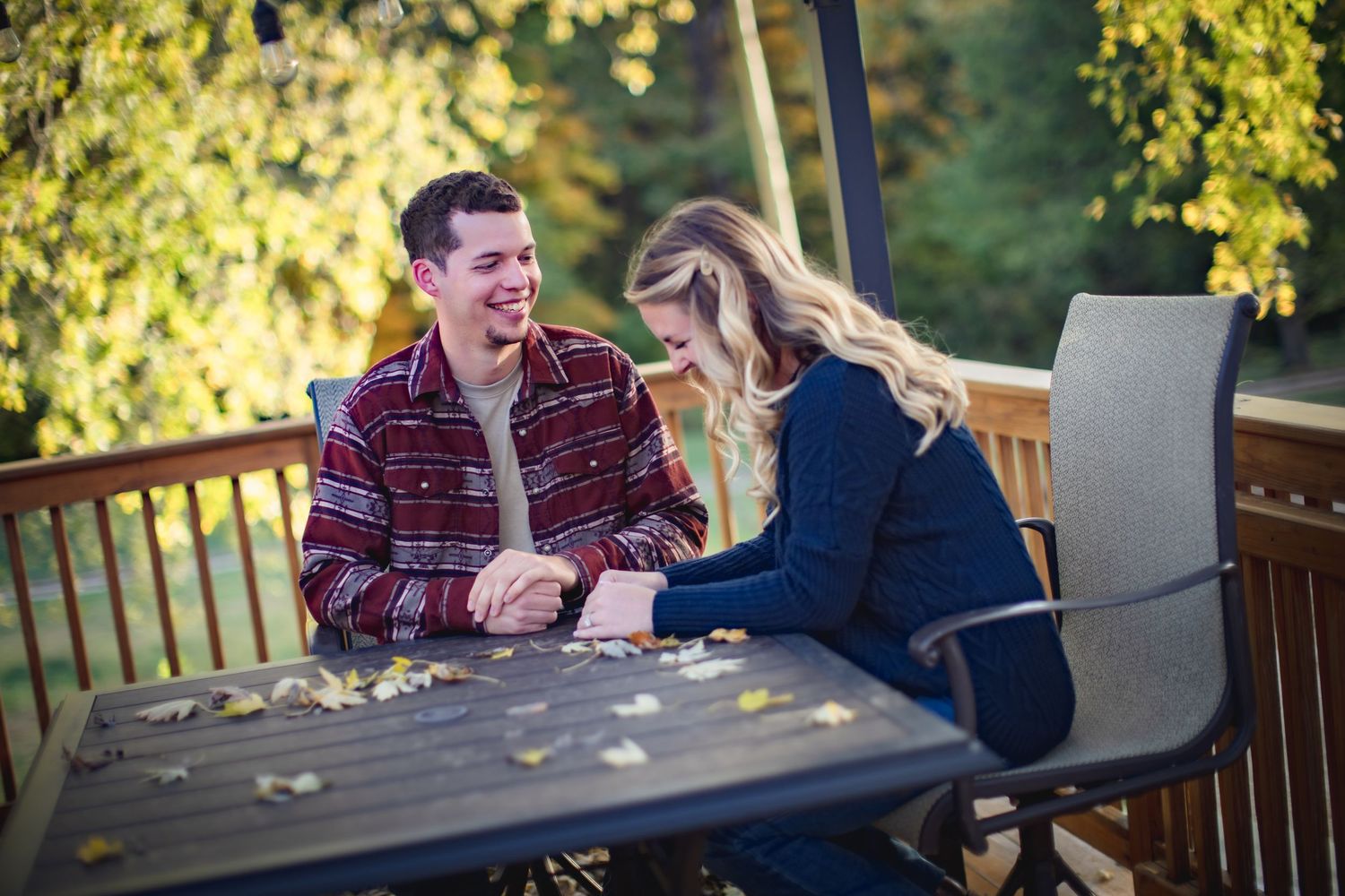 Two people engage in playful conversation on outdoor deck with golden sunlight.