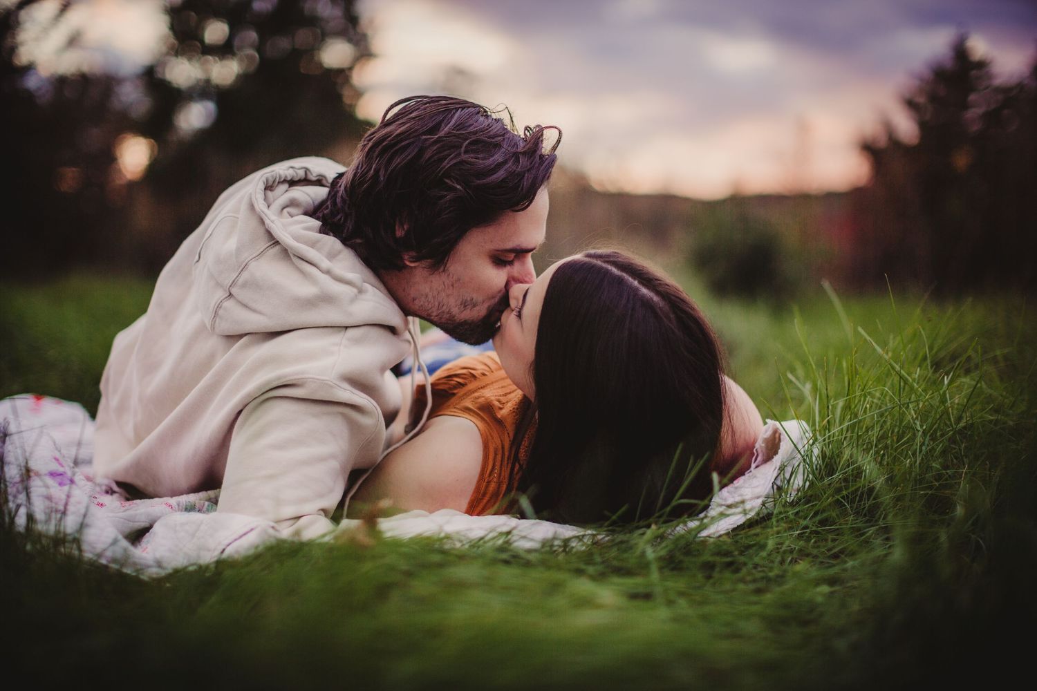 A tender moment photographed in nature with muted tones and gentle bokeh effects.