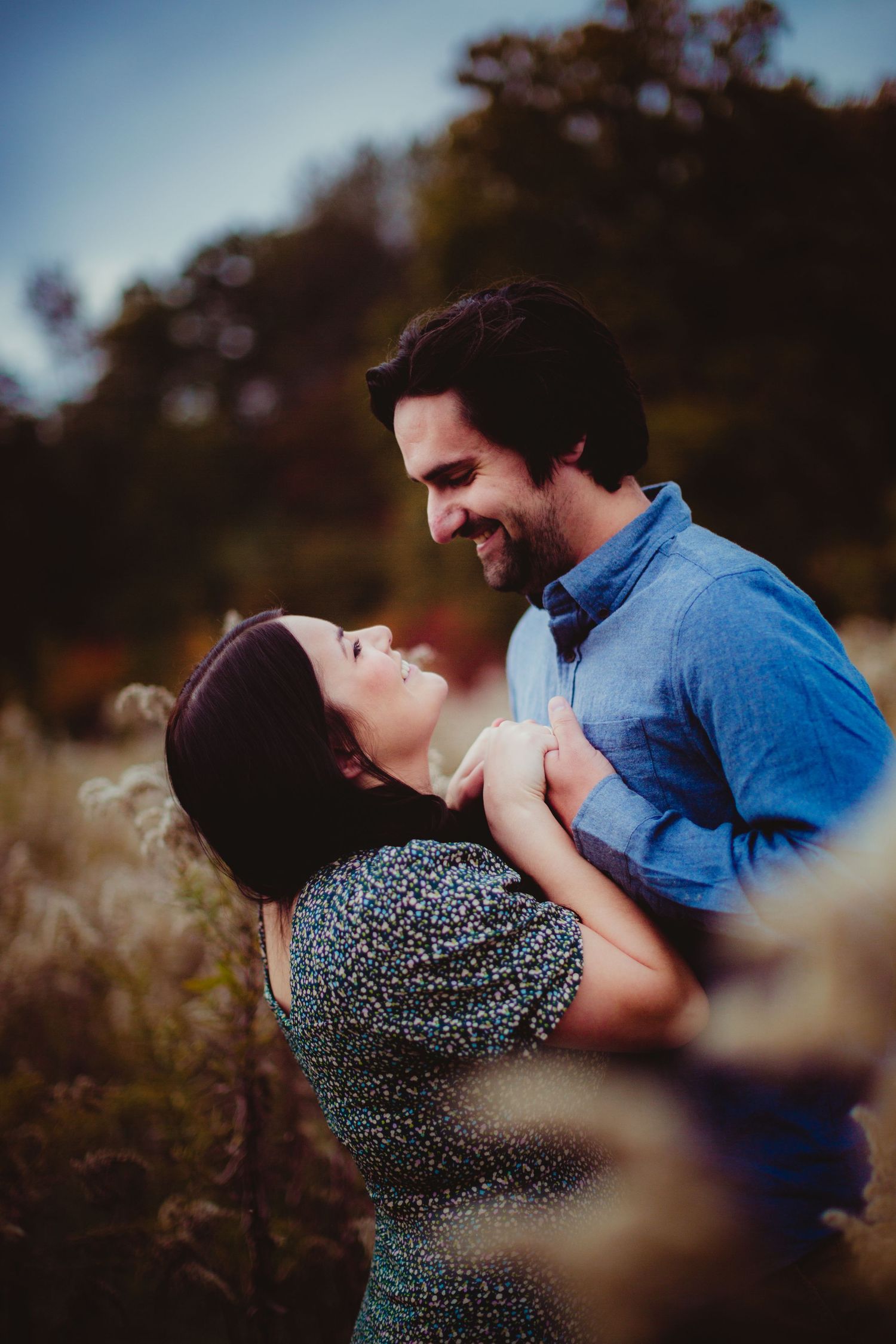 Couple's romantic embrace captured in dreamy autumn field setting.