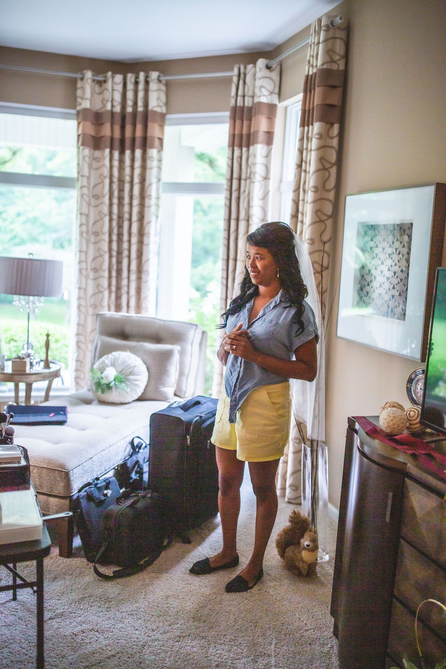 Casual dressed woman checking phone in living room with bay windows.