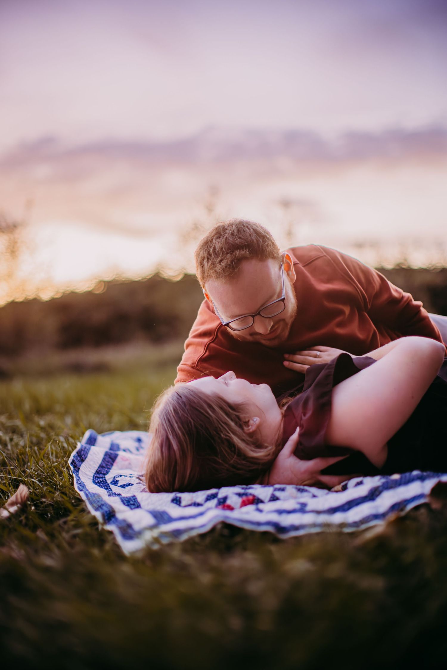 Sunset engagement photography session showing intimate moment on blanket.