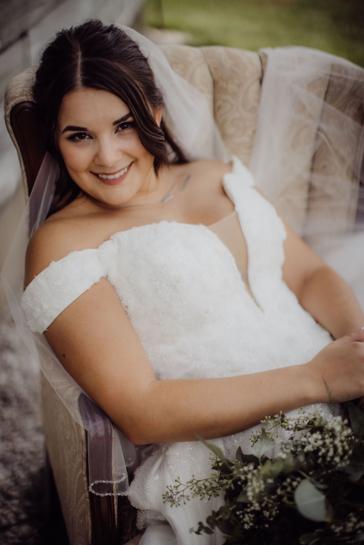 Romantic bridal portrait showcasing off-shoulder wedding dress and natural bouquet.